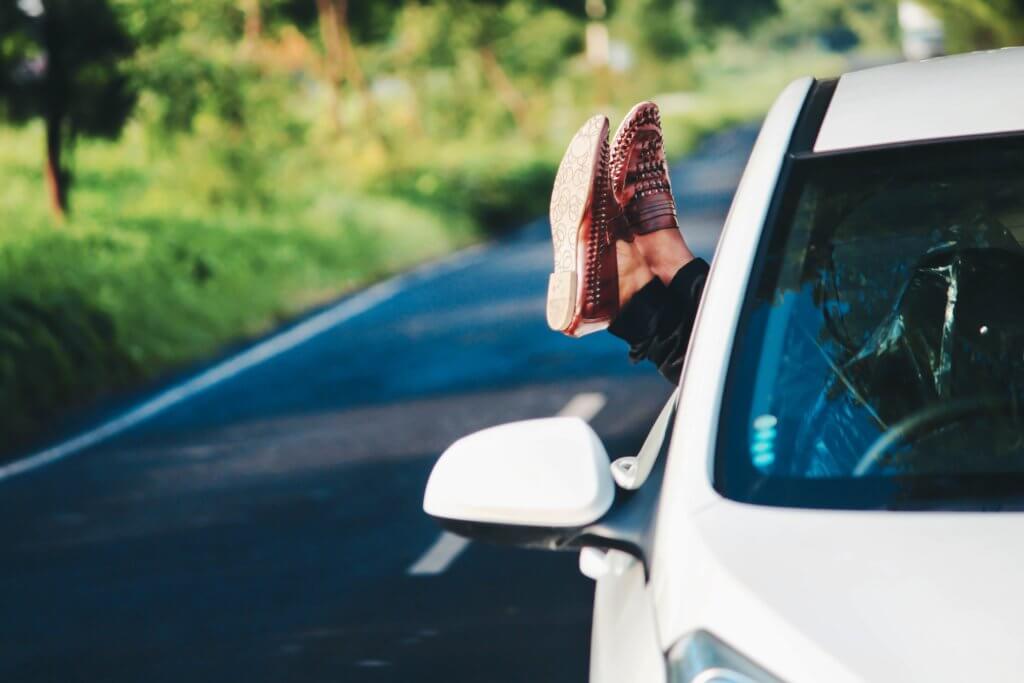 Feet hanging out of a car window to illustrate Self-Driving Cars: Safety, Security & Ethics lessons to be learnt